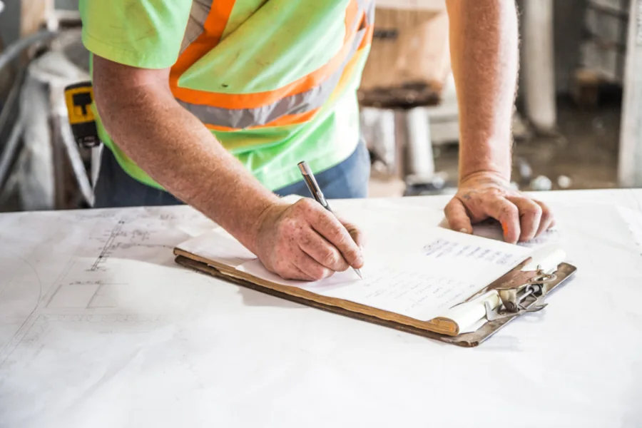A site worker filling in a checklist on a clipboard